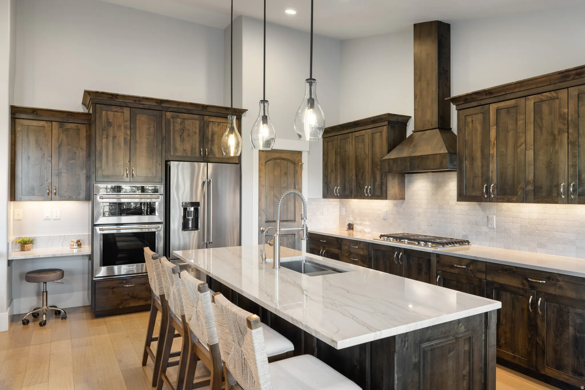 Spacious kitchen featuring dark wood cabinetry, stainless steel appliances, a generous island with seating, a gas cooktop, and light wood-finish flooring