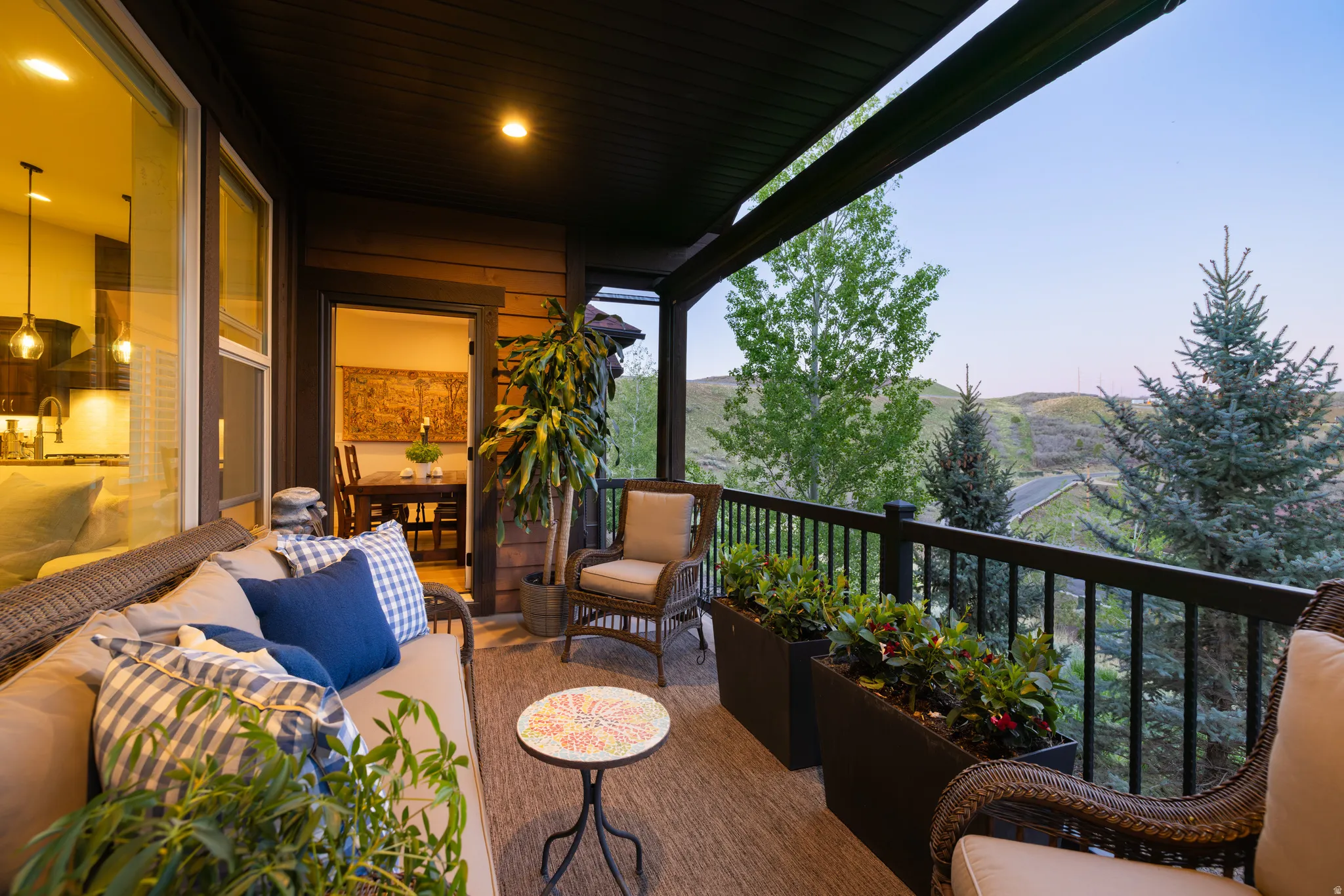 Covered outdoor balcony featuring a dark wood ceiling, wood-finish siding, and a black railing