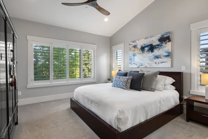 Vaulted ceiling bedroom featuring a large window with plantation shutters, recessed lighting, and a contemporary ceiling fan
