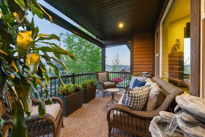 Covered outdoor patio featuring wood-finish siding, a dark soffit ceiling, and a black wrought-iron railing