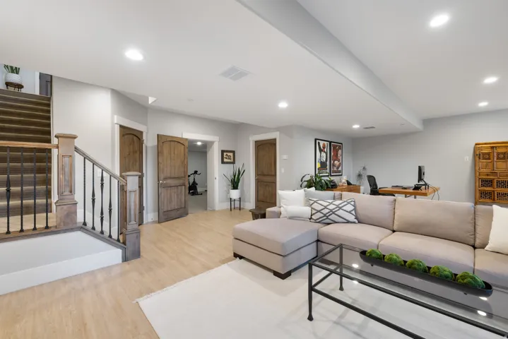 Spacious finished basement featuring light wood-finish flooring and recessed lighting