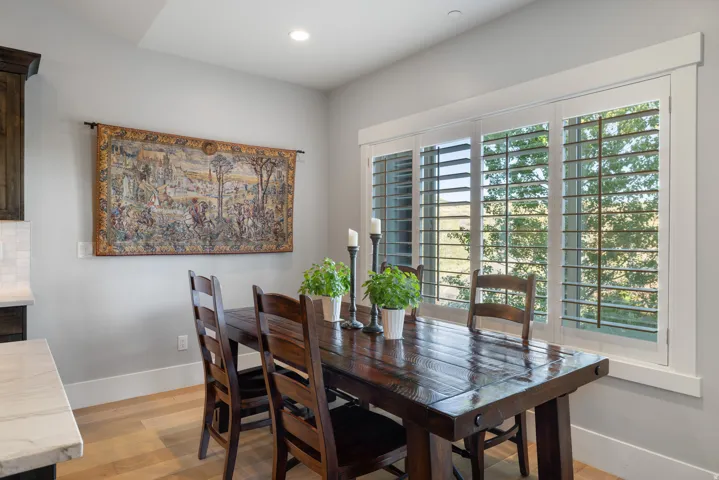 Dining area featuring wood-finish flooring, a large window with plantation shutters, recessed lighting, and a neutral wall color