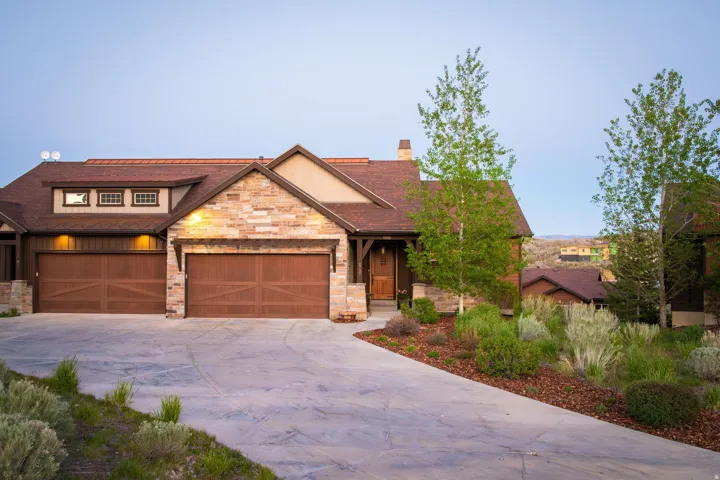Stone and wood-sided residence featuring a multi-gabled roofline and a concrete driveway