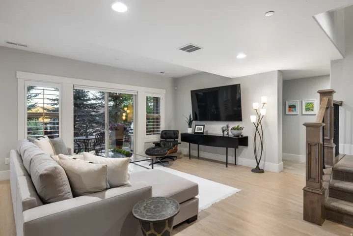 Spacious living area featuring light wood-finish flooring, recessed lighting, and a sliding glass door providing access to an exterior patio