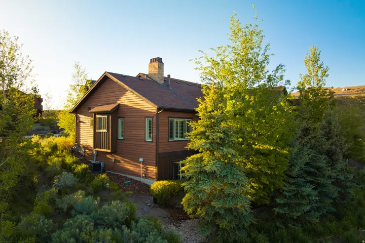Brown siding exterior with a dark shingle roof, a brick chimney, and a bay window
