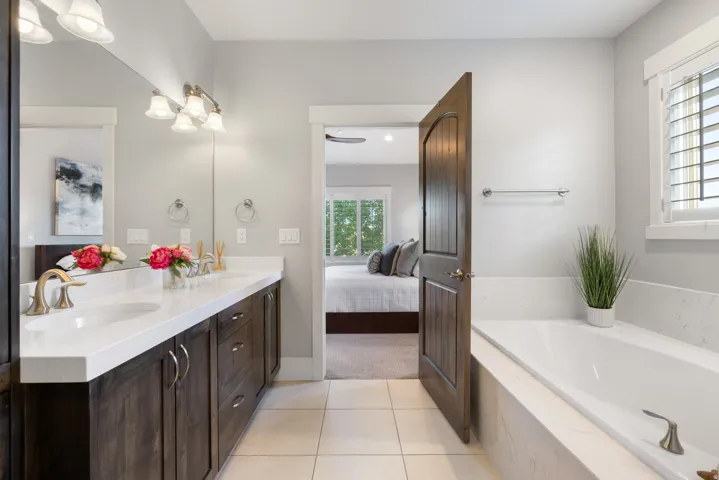 Double vanity with white undermount sinks and bronze-finish faucets, set in a light-toned countertop