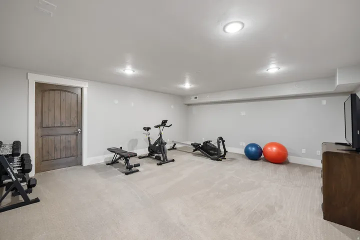 Spacious room featuring neutral carpeting, recessed lighting, and a paneled wood door with white trim