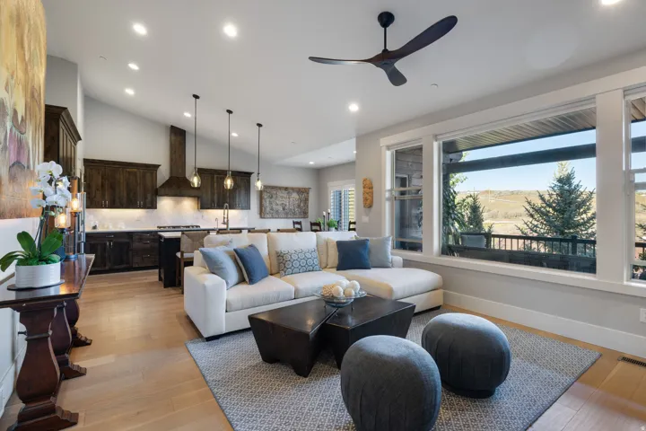 Open-concept living space featuring wood-finish flooring, a vaulted ceiling with recessed lighting and a modern ceiling fan, and large windows