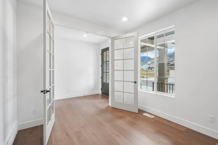 Interior room with wood-finish flooring, white walls, and recessed lighting