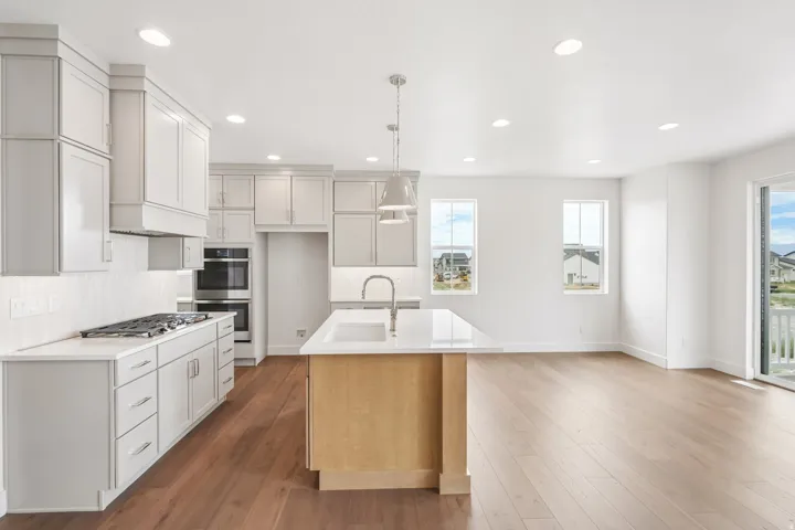 Open-concept kitchen and living area featuring wood-finish flooring, recessed lighting, and a kitchen island with a built-in sink