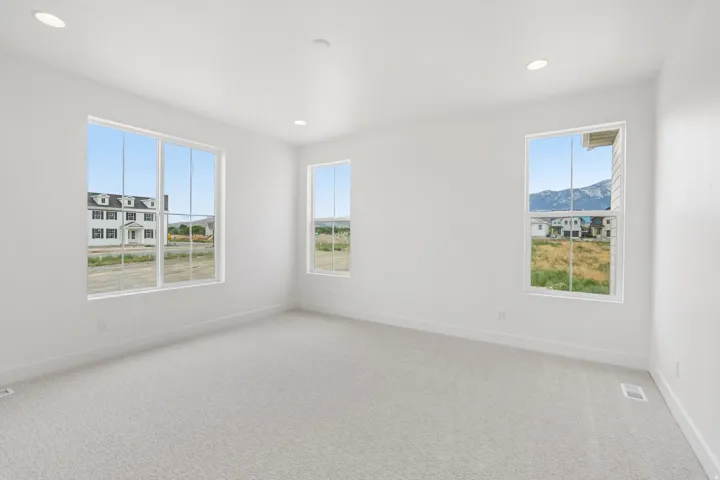Bright interior space featuring white walls and light-toned carpet flooring