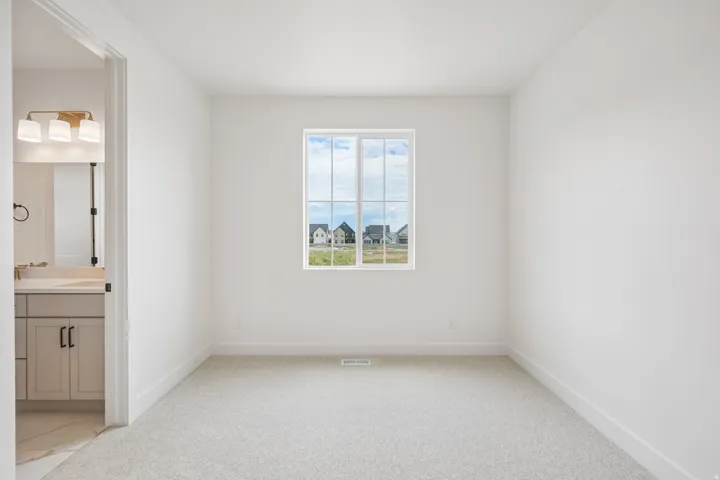 Bright interior space featuring a grid window, light-toned carpeting, and white baseboards