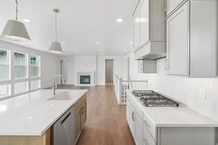 Modern kitchen featuring quartz countertops, a gas cooktop, and light-toned cabinetry