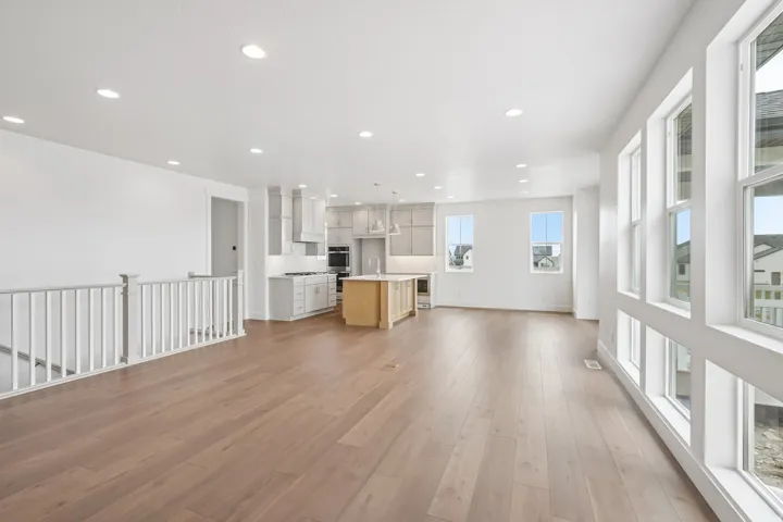 Open-concept living area with wood-finish flooring, recessed lighting, and an abundance of natural light from large windows