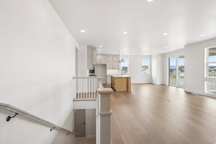 Open-concept living space featuring wood-finish flooring, recessed lighting, and a kitchen with light-toned cabinetry and a central island
