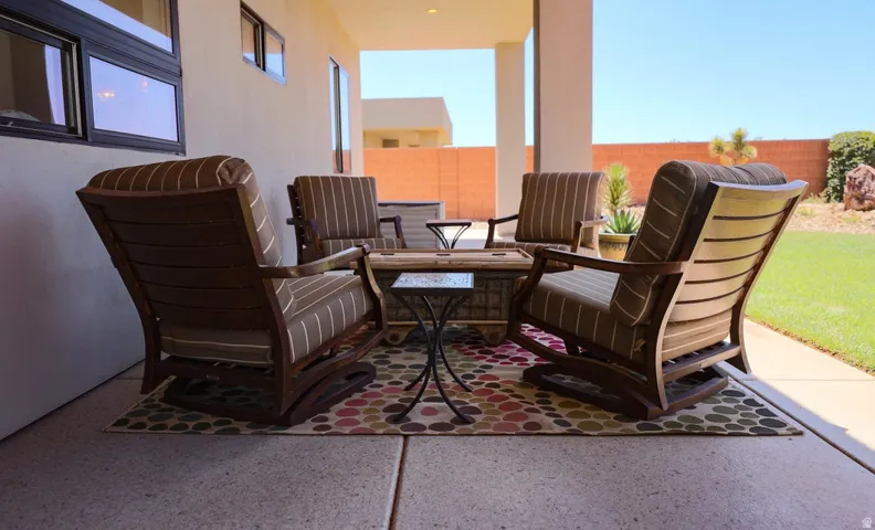 Covered patio with a concrete finish, adjacent to a manicured lawn