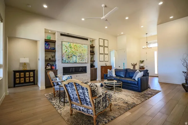 Open-concept living space featuring wood-finish flooring, recessed lighting, and a linear fireplace with a stone surround