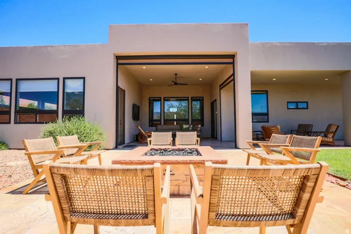Expansive stone patio with a built-in fire pit, covered outdoor living area, and a secondary covered patio