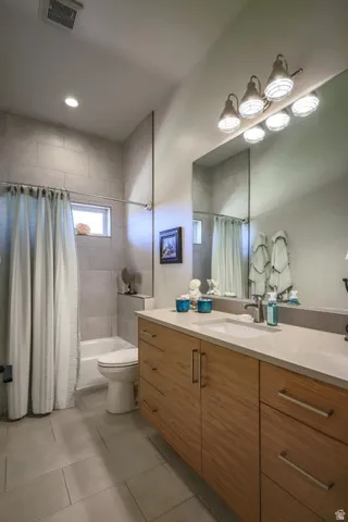 Full-size vanity with wood-finish cabinetry, integrated rectangular sink, and light-toned countertop