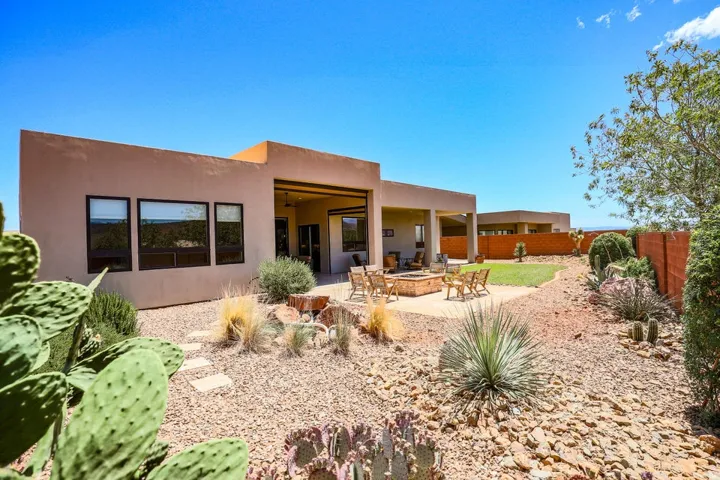 Expansive xeriscaped yard with a manicured lawn area, a paved patio, and a built-in fire pit