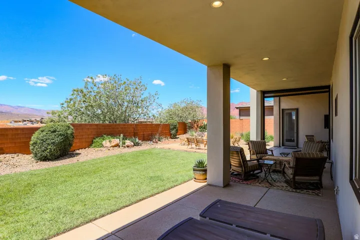 Expansive covered patio with recessed lighting, concrete flooring, and direct access to a manicured lawn