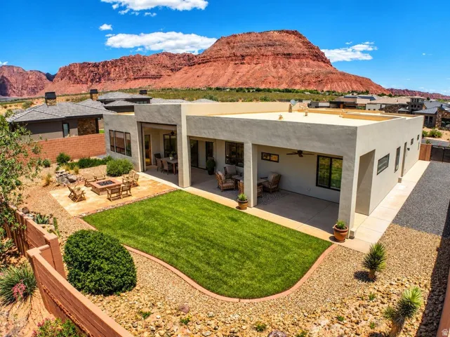 Expansive backyard featuring a manicured lawn, a fire pit area with paver patio, and two covered patio spaces