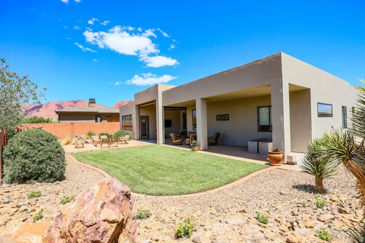 Expansive backyard featuring a manicured lawn, gravel pathways, and a covered patio area