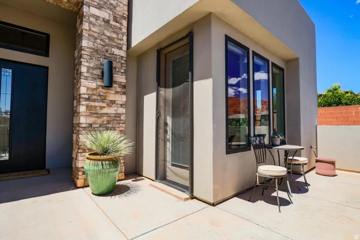 Stucco exterior with a stone accent column and a wall-mounted exterior light fixture