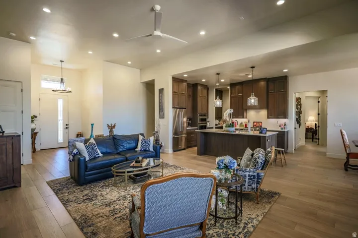 Open-concept living space featuring wood-finish flooring, recessed lighting, a ceiling fan, and a kitchen with dark wood-finish cabinetry and a central island