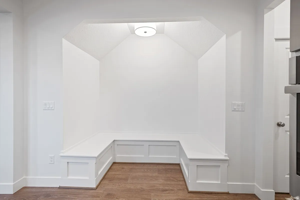 Built-in bench seating with panel detailing, wood-finish flooring, recessed lighting, and a neutral color palette