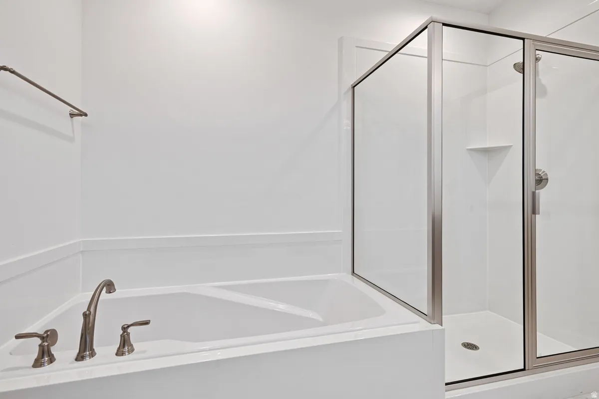 Built-in soaking tub with bronze-finish fixtures, complemented by a separate glass-enclosed shower featuring a shower niche and white tile-look surround