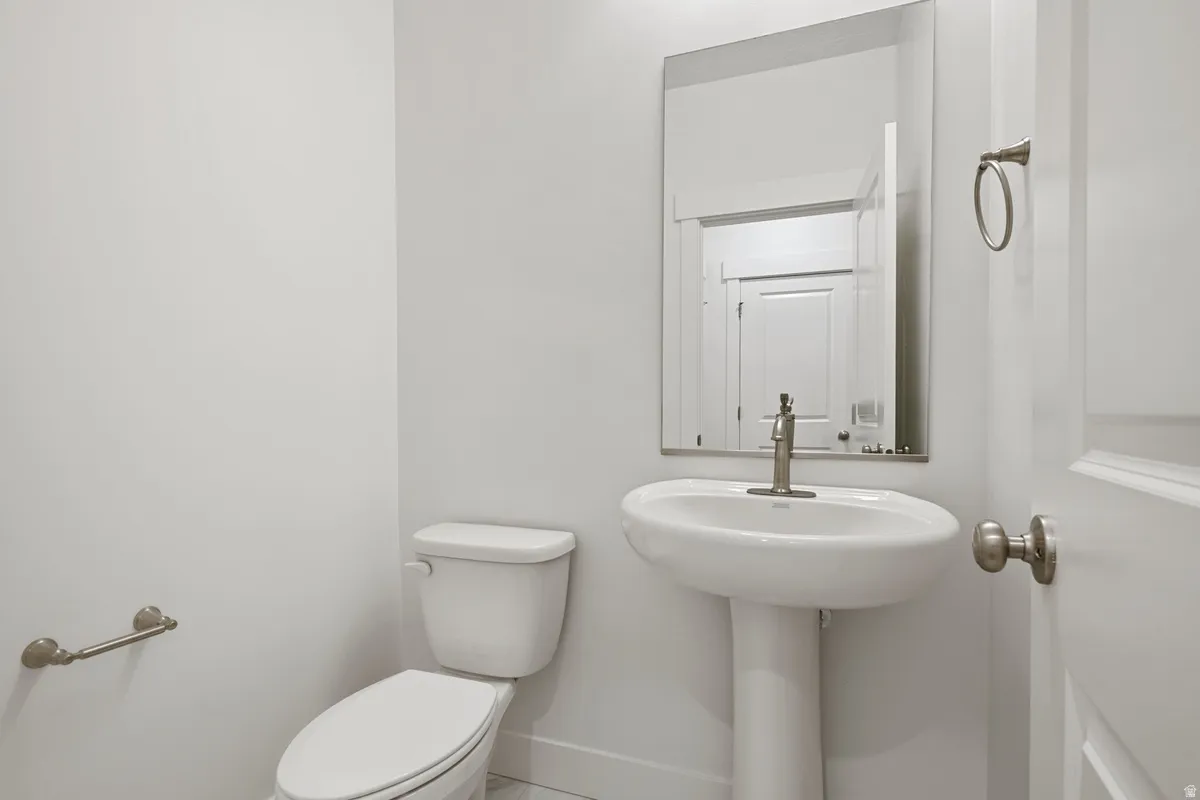 Pedestal sink with a brushed nickel faucet, framed mirror, and coordinating towel ring