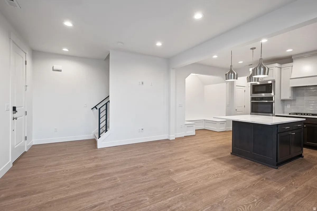 Open-concept living space featuring wood-finish flooring, recessed lighting, and a modern kitchen