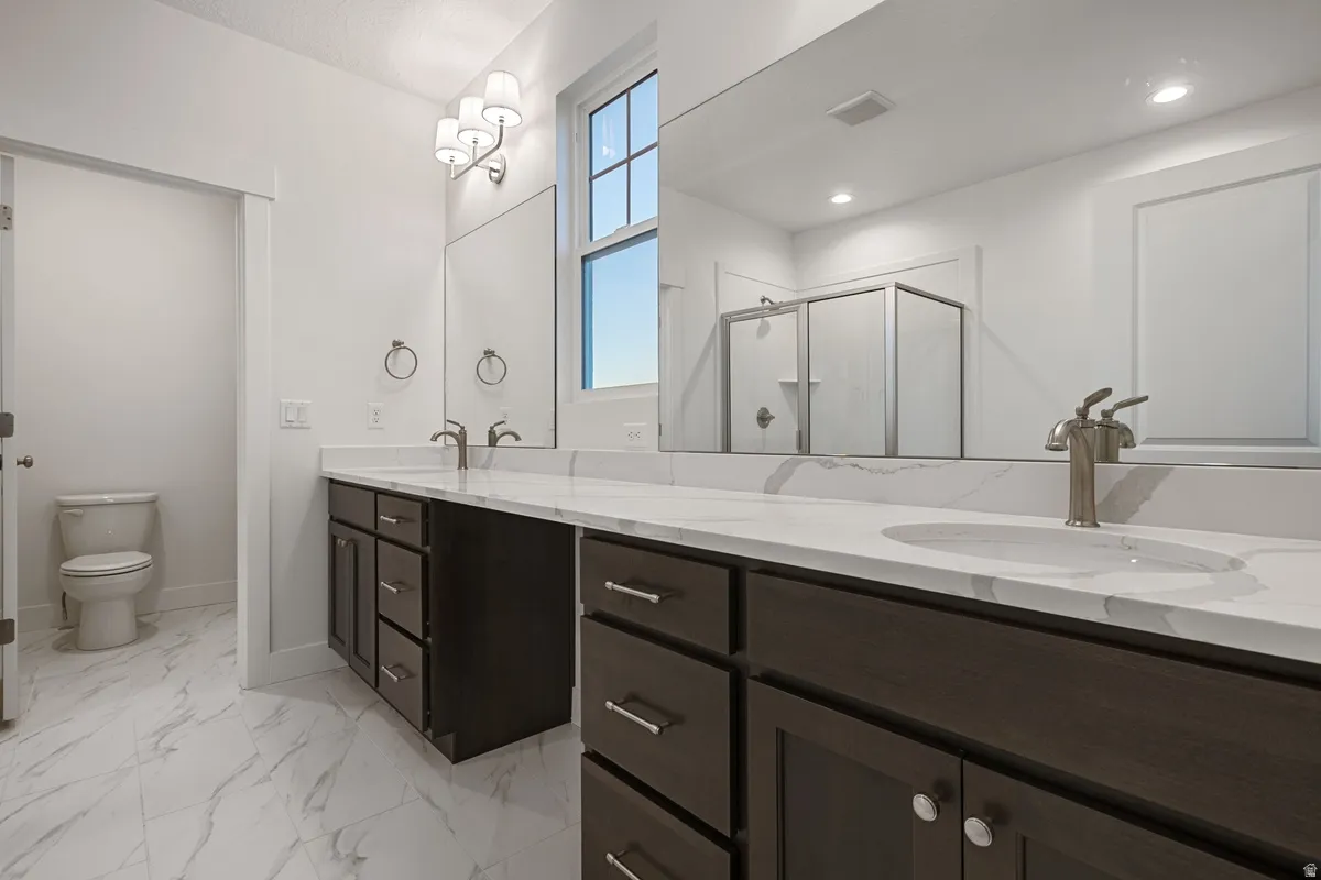 Dual vanity with white stone-finish countertops, undermount sinks, and dark wood cabinetry