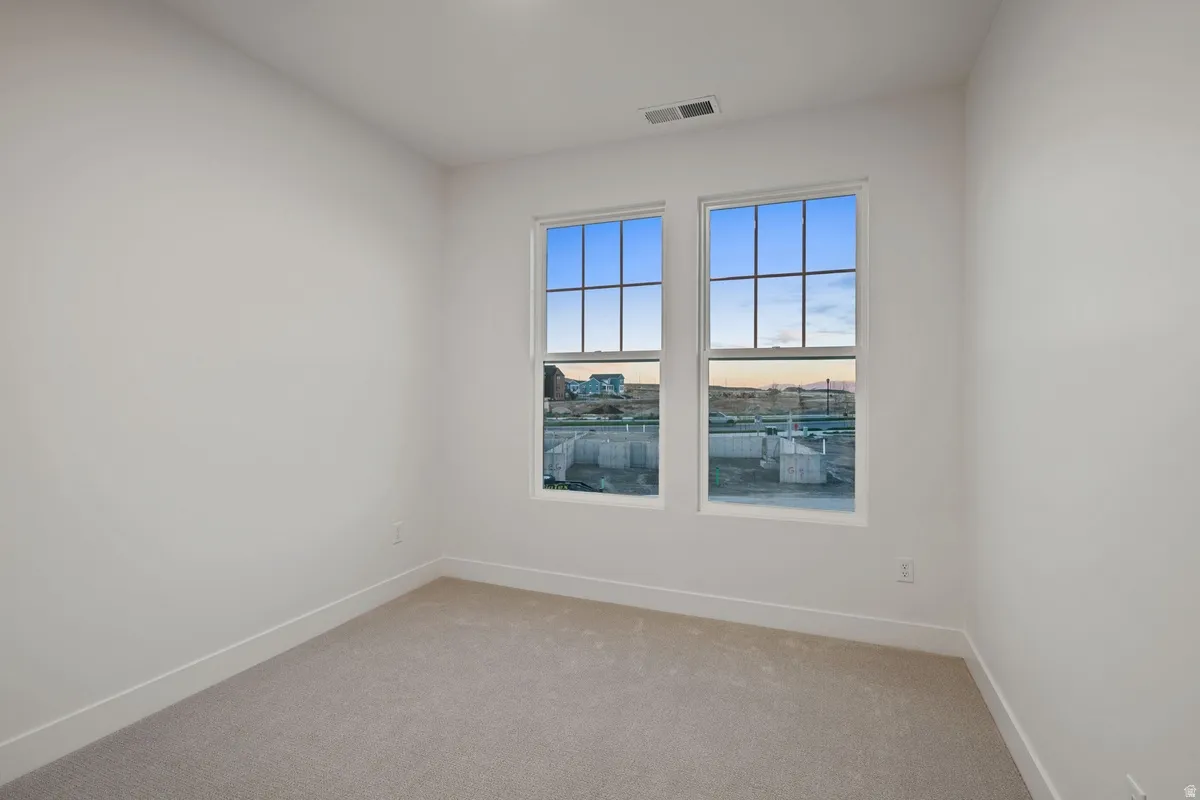 Carpeted room featuring two large windows with grid patterns, white walls, and white baseboard trim