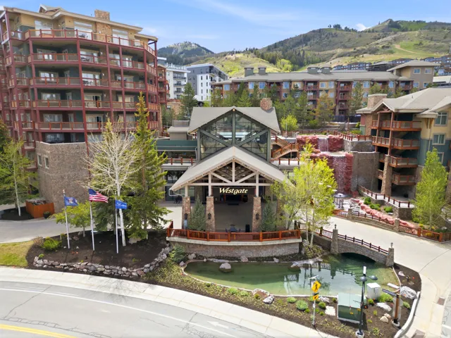 Multi-story building featuring extensive balconies, a prominent main entrance, and stone accents
