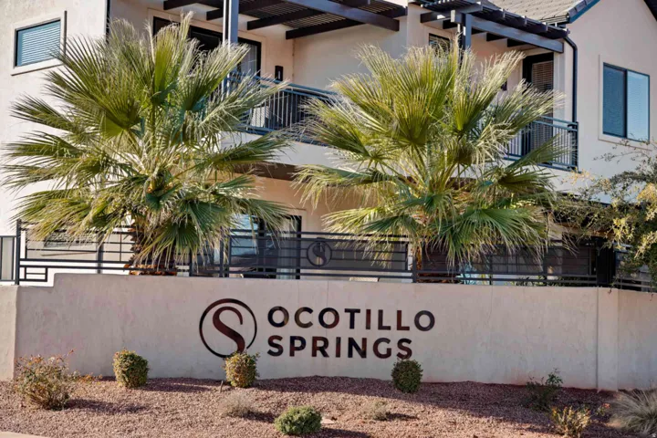 Entry monument featuring the property name, "Ocotillo Springs," set against a desert-style landscape with gravel and low-lying shrubs