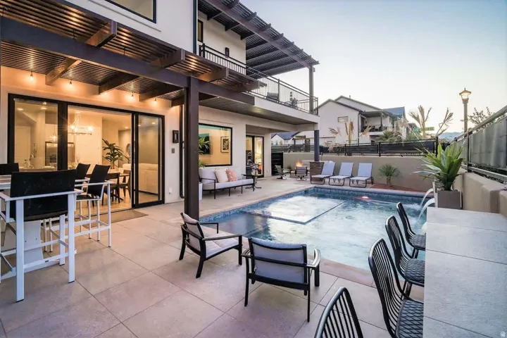 Outdoor living space featuring a custom-shaped pool with integrated spa and waterfall, surrounded by concrete paver patio