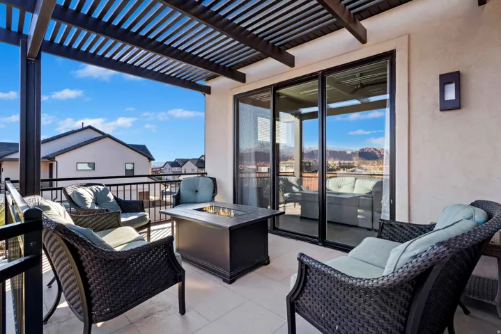 Outdoor patio featuring a slatted pergola, tile flooring, and a black metal railing