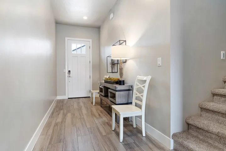 Entryway featuring a white paneled door with upper glass inserts, wood-finish flooring, recessed lighting, and a carpeted staircase