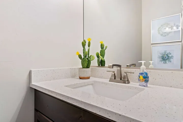 Vanity with an integrated rectangular sink, light speckled countertop, dark wood-finish cabinetry, and a brushed nickel faucet
