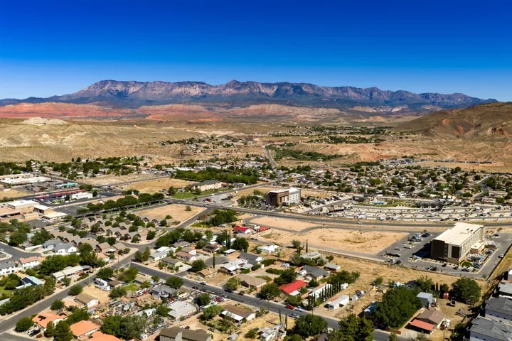 Expansive desert landscape featuring distant mountains and a residential area with varied rooflines