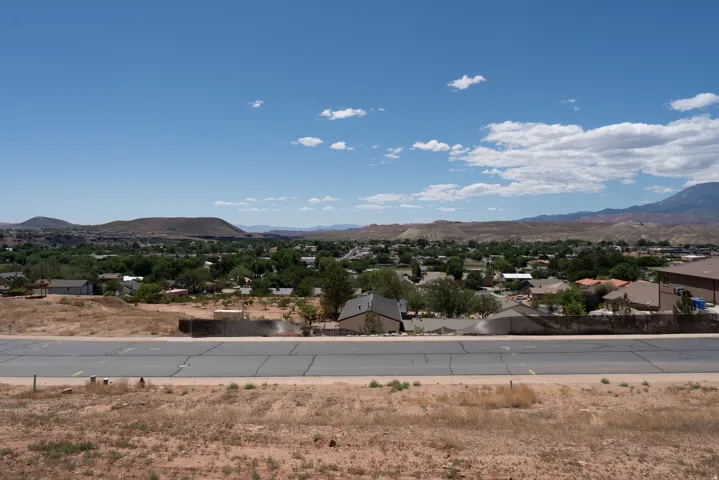 Expansive desert landscape featuring distant mountains and a residential community with lush green trees
