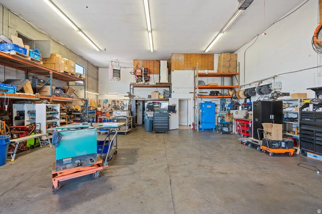 Expansive commercial space featuring high ceilings, concrete flooring, extensive overhead fluorescent lighting, and industrial-grade shelving systems
