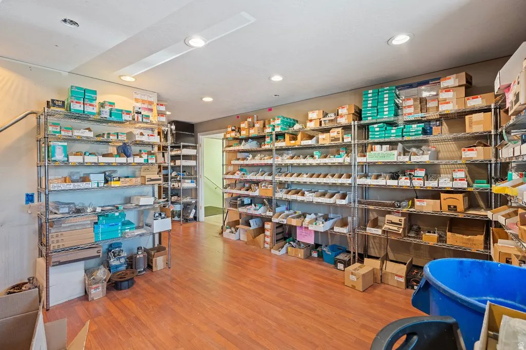 Spacious interior room featuring wood-finish flooring, recessed lighting, and extensive metal shelving units