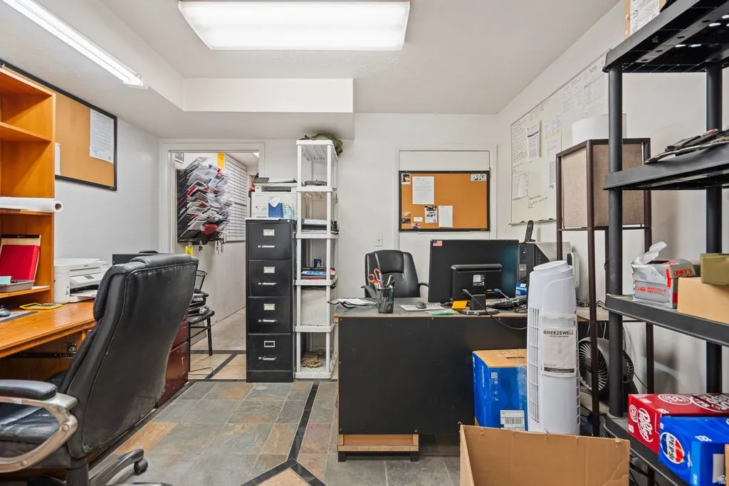 Functional workspace featuring slate tile flooring with decorative inlay, overhead fluorescent lighting, and white walls
