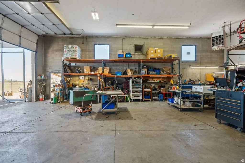 Spacious industrial interior featuring a concrete floor, high ceilings with fluorescent lighting, and block wall construction