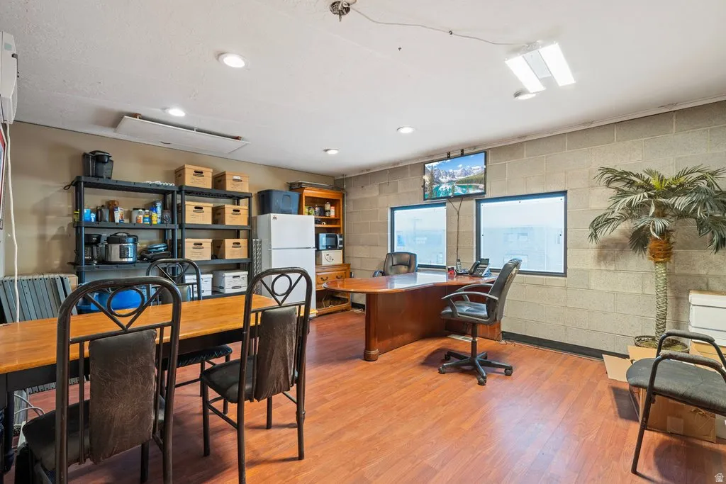 Spacious room featuring wood-finish flooring, block wall construction, and multiple windows for natural light