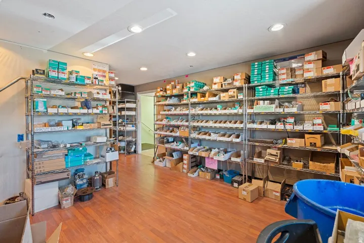 Spacious interior room featuring wood-finish flooring, recessed lighting, and extensive metal shelving units