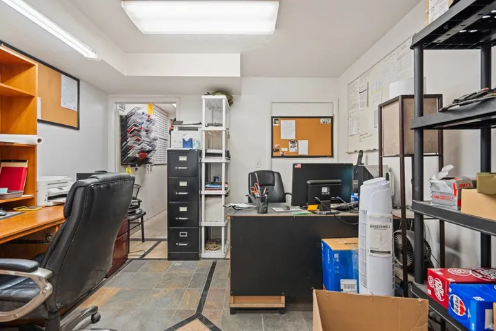 Functional workspace featuring slate tile flooring with decorative inlay, overhead fluorescent lighting, and white walls